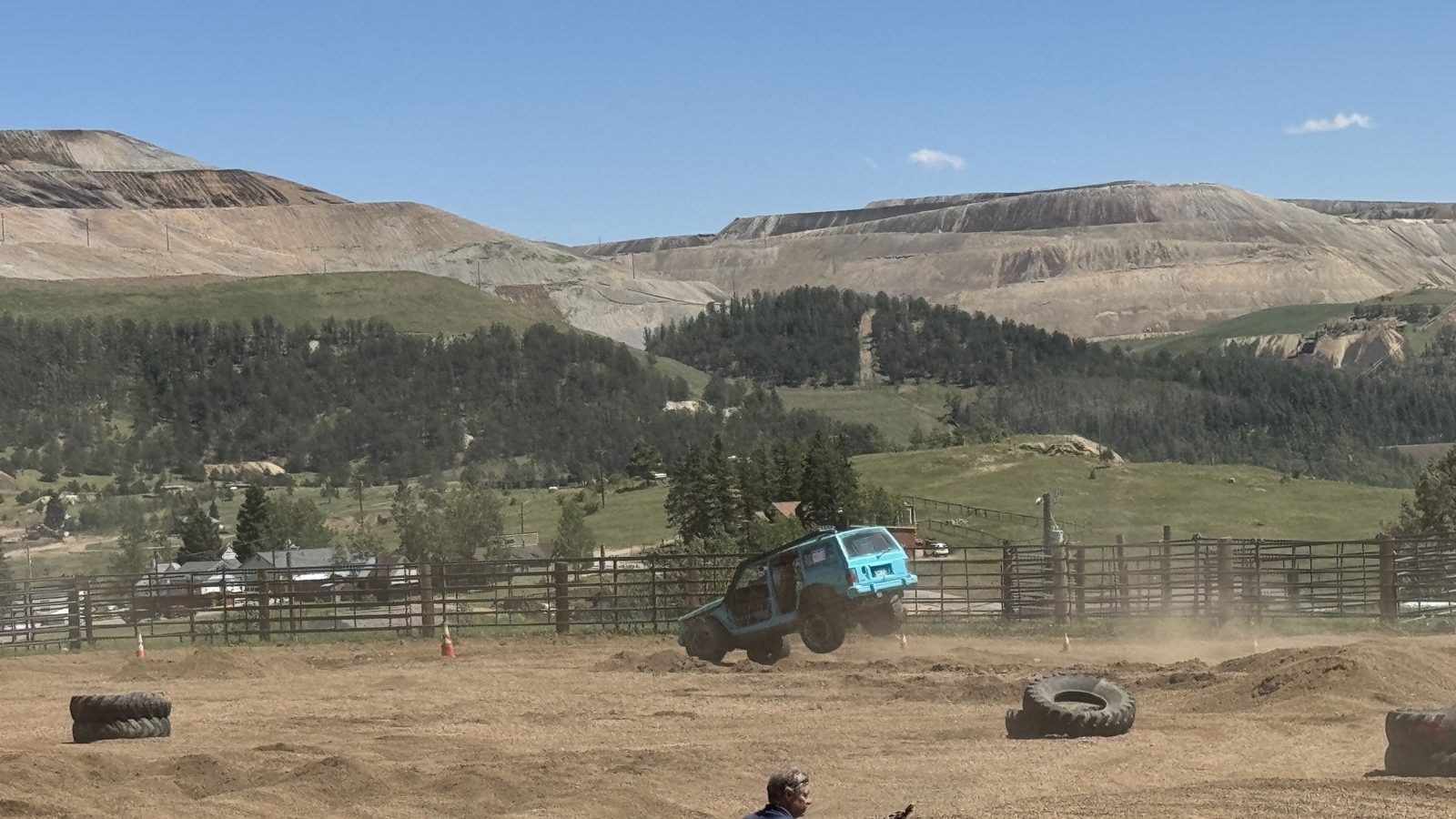 A tough-truck competitor catching air on the dirt course at the Teller County Fair, with the Cripple Creek gold-mine terraces rising behind